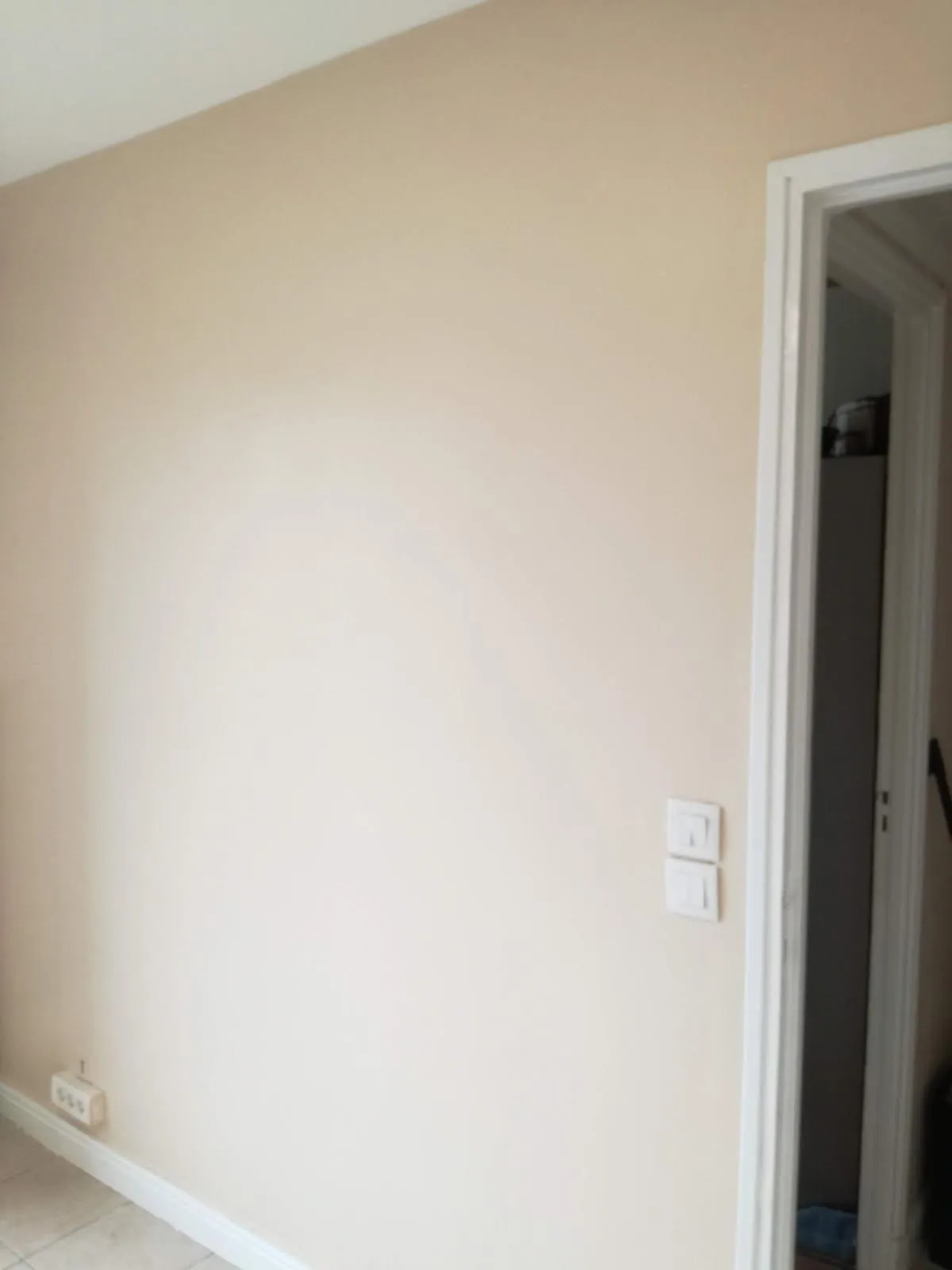 Mur peint dans une teinte ivoire avec encadrement de porte et plinthe blancs