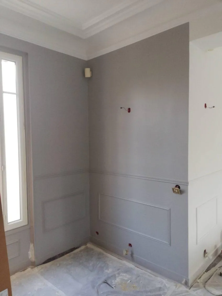 Murs et soubassements gris avec moulures blanches, sol protégé pendant les travaux