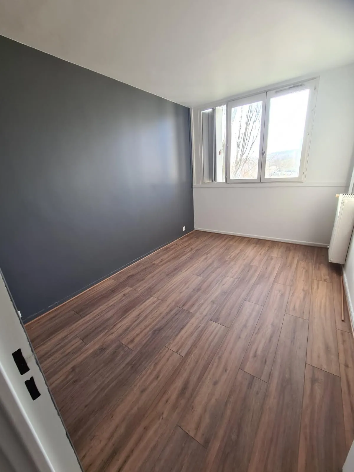 Chambre aux murs blanc et anthracite, éclairée par une fenêtre